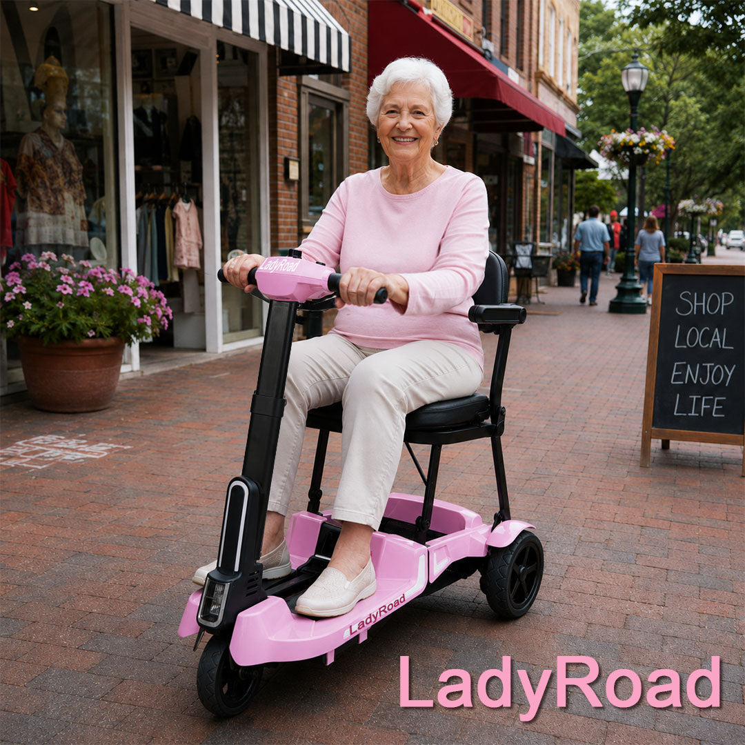 Smiling older woman rides a pink LadyRoad mobility scooter on a brick-lined shopping street, beside flowers and a “Shop Local” sign.